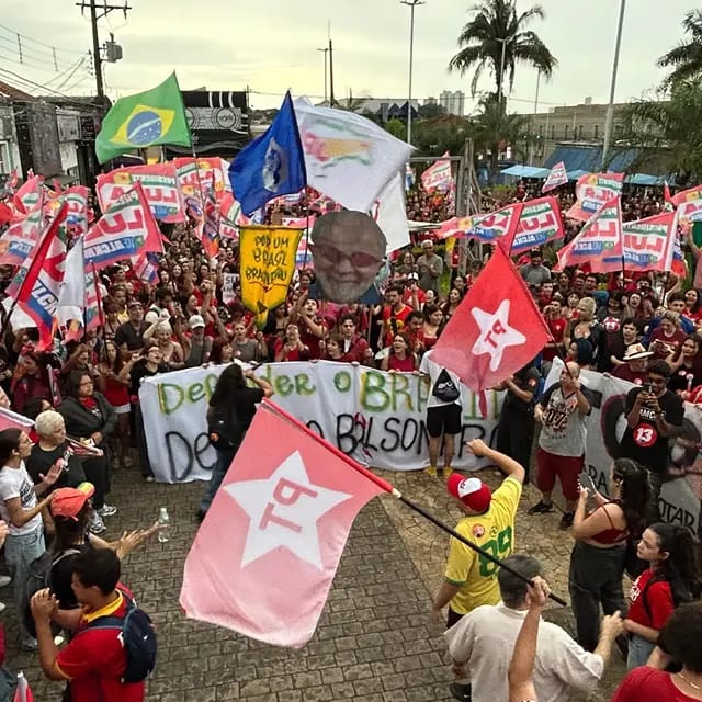 Manifestantes com camisetas vermelhas e bandeiras ocupam rua do centro de Araraquara em ato político.