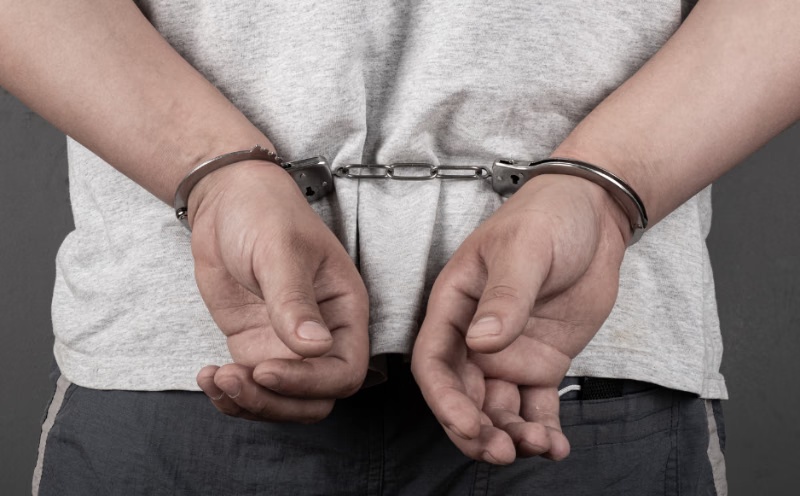 Homem algemado com as mãos para trás