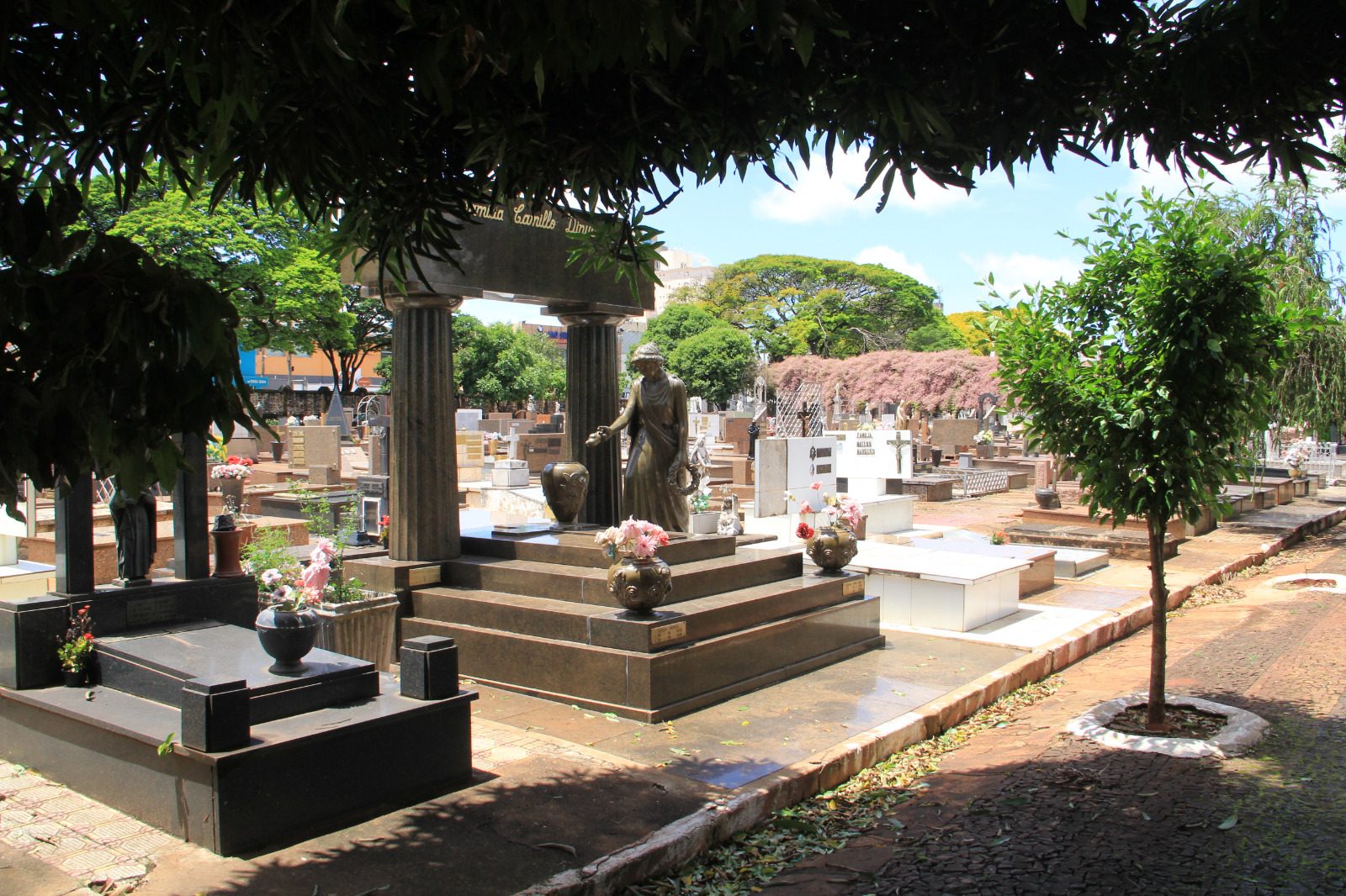 Mulher de chapéu e luvas lava um túmulo com escova e sabão em um cemitério