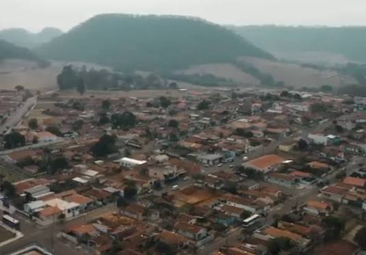 Captura de tela de um céu nublado com nuvens carregadas sobre um bairro residencial de Ribeirão Bonito, com árvores e casas ao fundo.