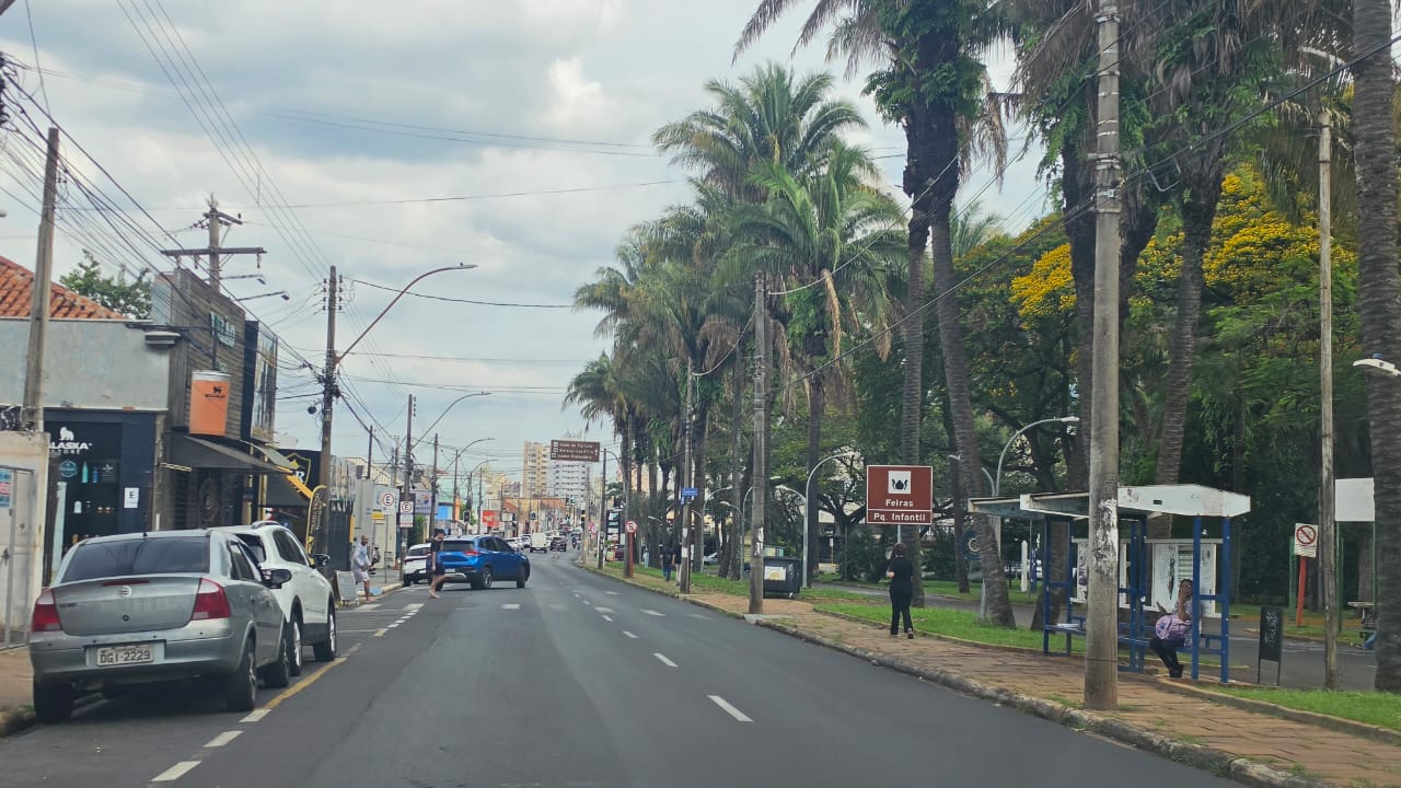 Céu limpo e sol forte sobre uma cidade no interior de São Paulo, com prédios baixos e árvores ao fundo