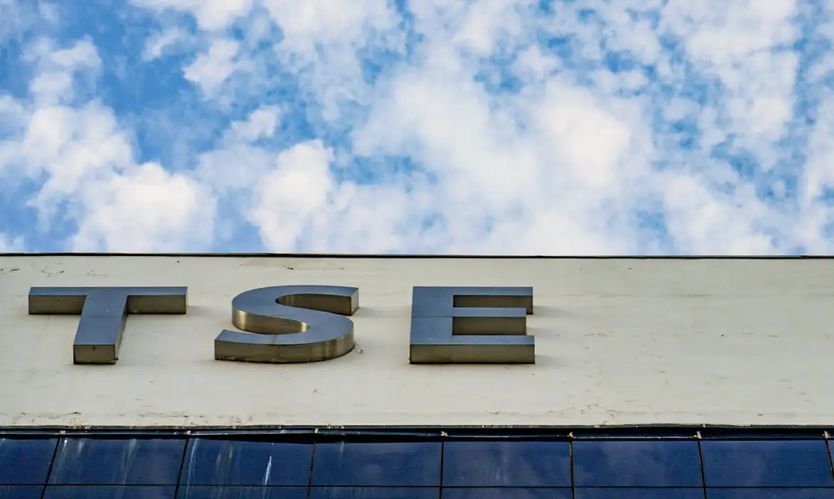 Plenário do TSE em Brasília, com logotipo da Meta em tela ao lado de documentos da Justiça Eleitoral.